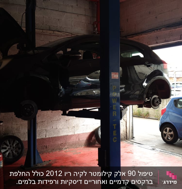 רכב מורם על ליפט במוסך עם מכסה מנוע פתוח